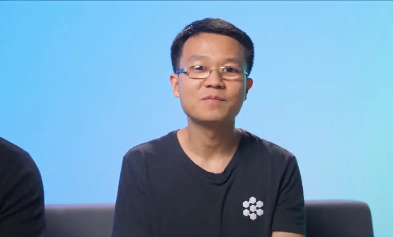 Person with glasses wearing black shirt against blue gradient background.