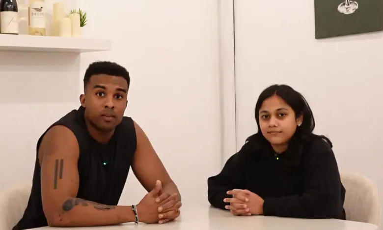 Two people sit at a table, looking directly at the camera.