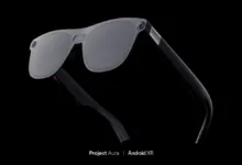 XREAL Project Aura Android XR glasses with gray lenses and black frames.