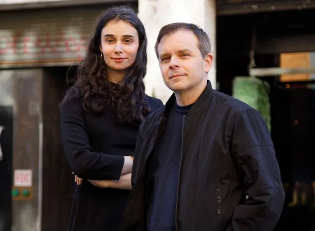 Laura Sisson and Sean Raspet stand outdoors against a brick building.