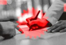 Hand signing a document with a pen, stylized in red and grayscale.