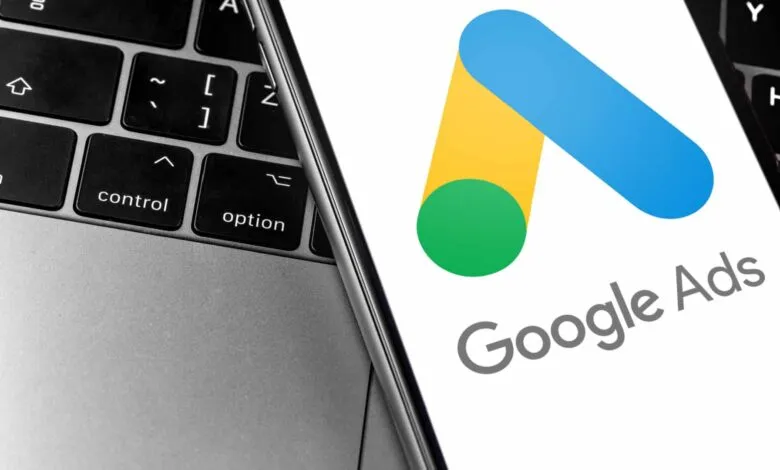 Google Ads logo displayed on a phone next to a laptop keyboard.