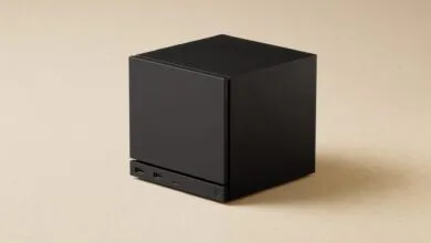 Black cube-shaped computer with ports on a neutral background.