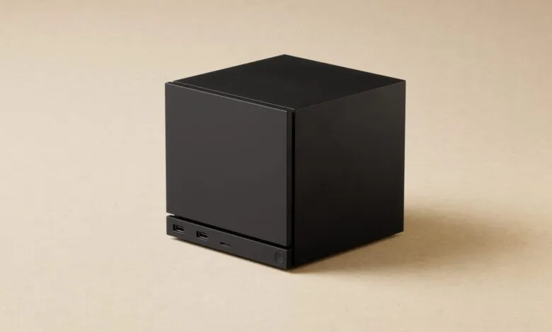 Black cube-shaped computer with ports on a neutral background.