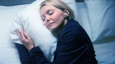 Woman in business suit sleeps peacefully in bed with earplugs.