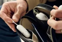 Hands placing AirFly Pro into a zippered pouch with earbuds.
