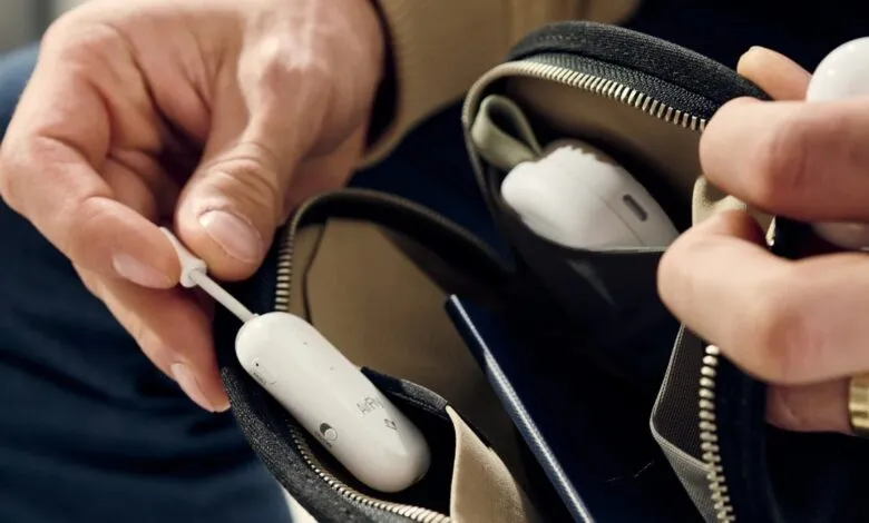 Hands placing AirFly Pro into a zippered pouch with earbuds.