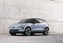 Light blue Volvo EX30 electric SUV parked against a concrete wall.