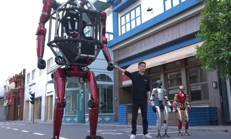 Large red mech robot with a man and two smaller robots on a city street.