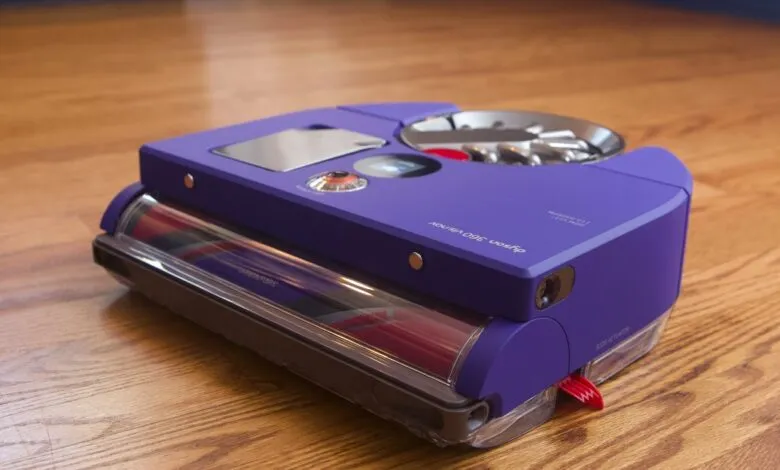 Purple Dyson 360 Vis Nav robot vacuum cleaner on hardwood floor.