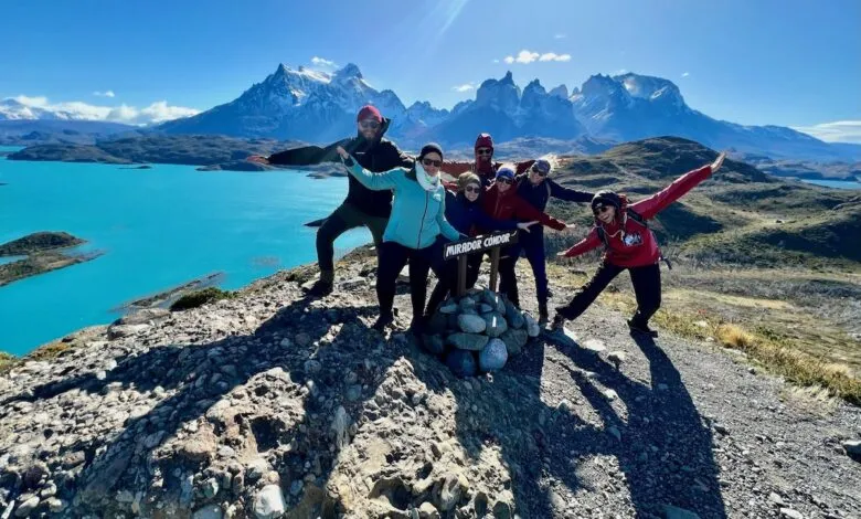 Group of hikers pose at Mirador Condor overlook in Patagonia with mountains and turquoise lake.