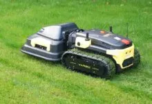Yarbo robot lawn mower cutting grass with track wheels.