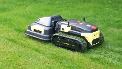 Yarbo robot lawn mower cutting grass with track wheels.