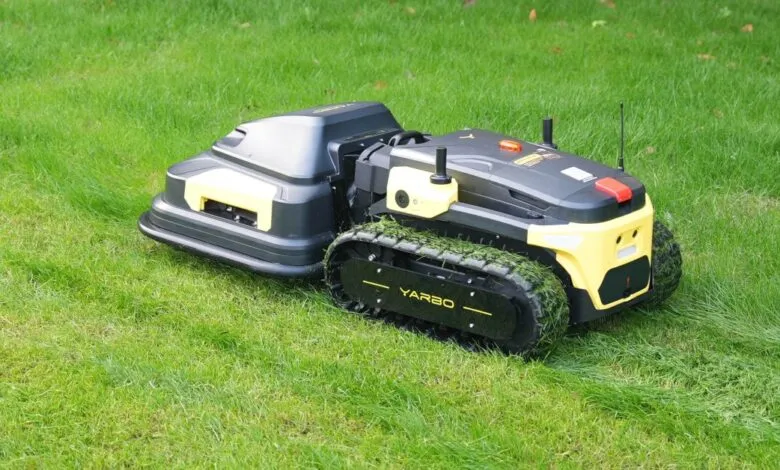 Yarbo robot lawn mower cutting grass with track wheels.