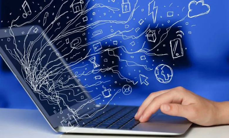 Laptop with hand typing, digital icons floating from the screen.