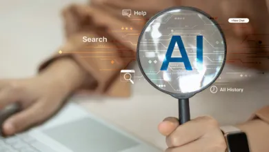 Magnifying glass over AI text, person types on laptop, search concept.