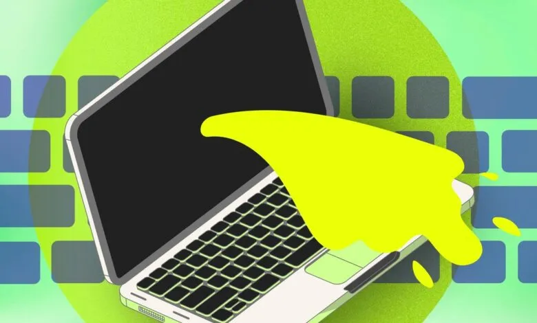 Laptop with yellow paint splash on keyboard, green background.
