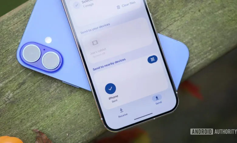 Two smartphones showing file sharing interface on a wooden surface.