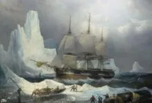 Tall ship navigating icy Arctic waters with crew in small boats.