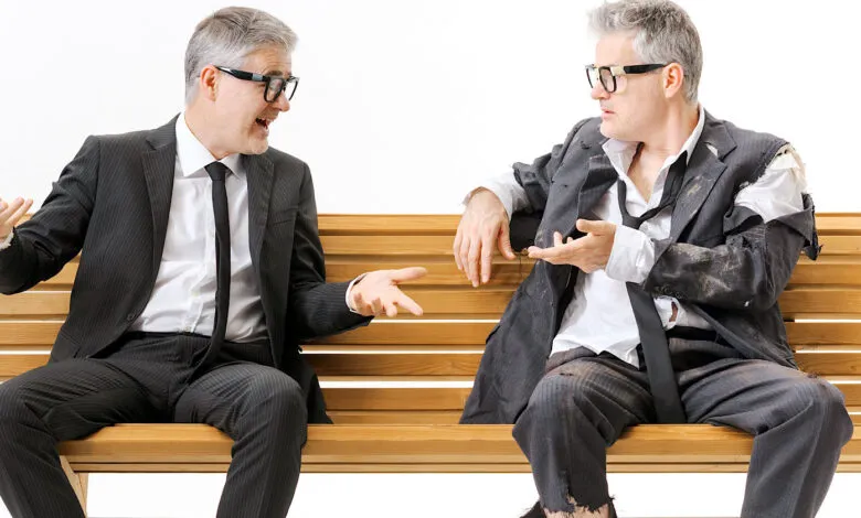 Businessman in suit talks to his homeless, tattered self on bench.