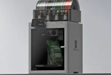Bambu Lab P1S 3D printer printing a green car with AMS filament system.