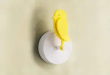 Yellow bird wall light fixture on a light yellow wall.