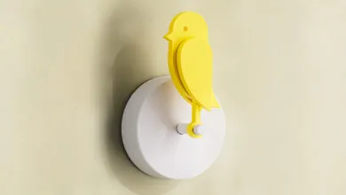 Yellow bird wall light fixture on a light yellow wall.