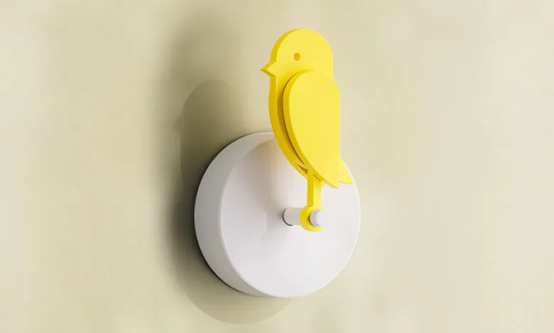 Yellow bird wall light fixture on a light yellow wall.