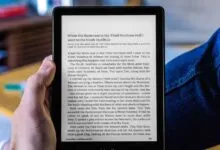 Person holds e-reader displaying text from a book, close-up view.