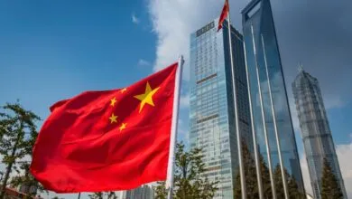 Chinese flag waving in front of Shanghai skyscrapers on a sunny day.