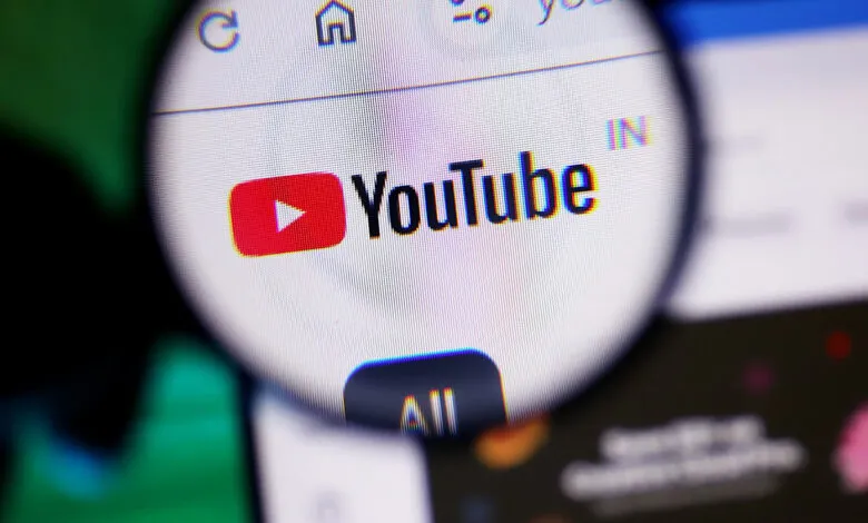 Magnifying glass over YouTube logo on a computer screen.