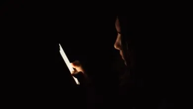 Person in the dark illuminated by the light of a smartphone screen.