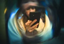 Woman intently looks at her phone, surrounded by blurred, swirling colors.