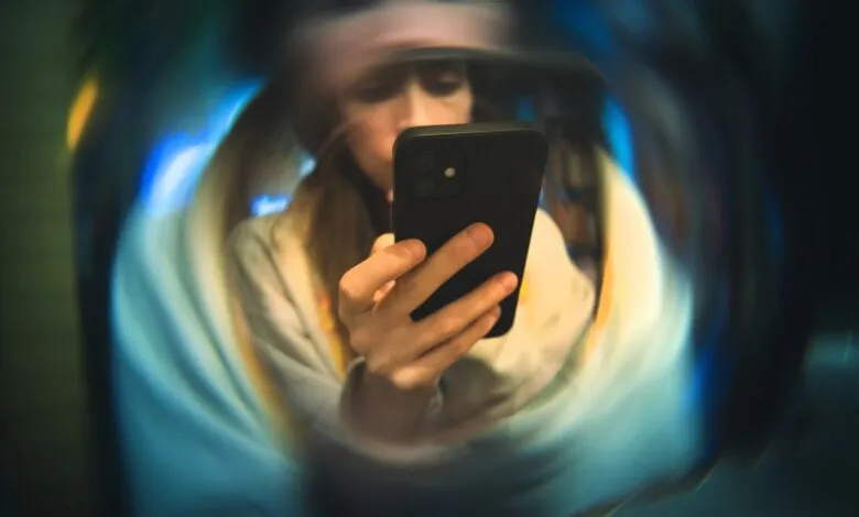 Woman intently looks at her phone, surrounded by blurred, swirling colors.