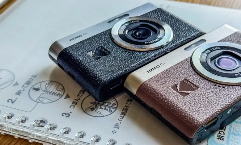 Two Kodak PIXPRO C1 cameras, one black and one brown, on a notebook.
