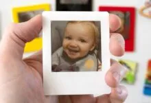 Hand holds a magnet with a smiling baby photo.