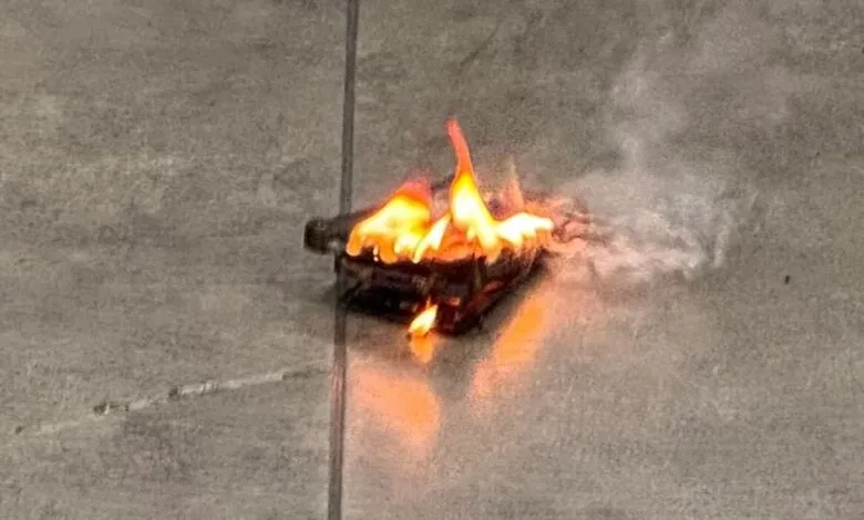 Burning device on tiled floor with flames and smoke visible.