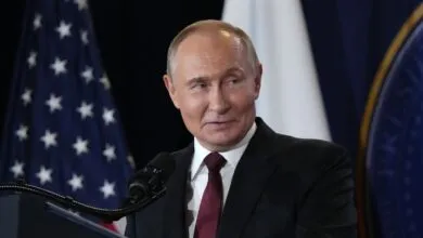 Vladimir Putin at podium with US flag backdrop.