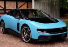 Light blue Ferrari coupe with black roof and gray wheels parked outside.