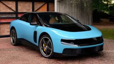 Light blue Ferrari coupe with black roof and gray wheels parked outside.