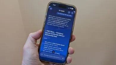 Hand holds iPhone displaying Copilot's summary of open browser tabs.