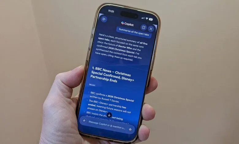 Hand holds iPhone displaying Copilot's summary of open browser tabs.