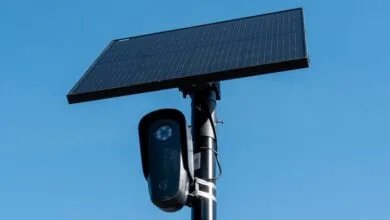 License plate reader camera with solar panel against a clear blue sky.
