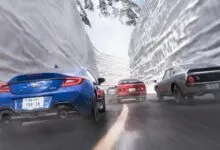 Cars racing through a snowy mountain pass, motion blur indicates speed.