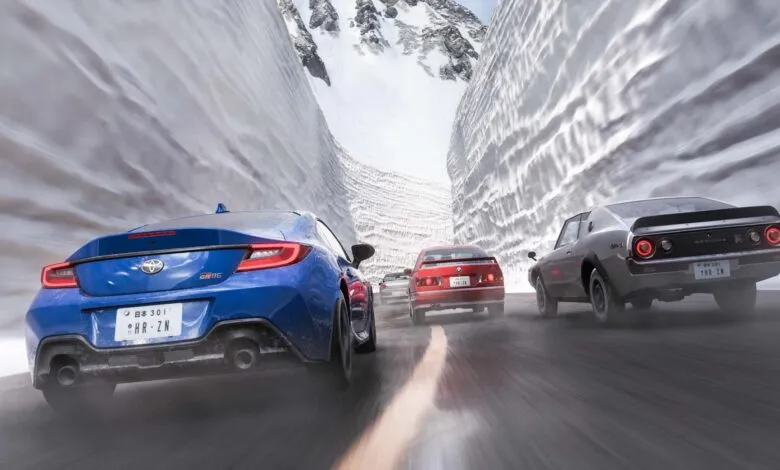 Cars racing through a snowy mountain pass, motion blur indicates speed.