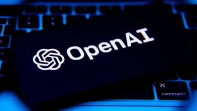 OpenAI logo and text displayed on a dark screen atop a laptop keyboard.