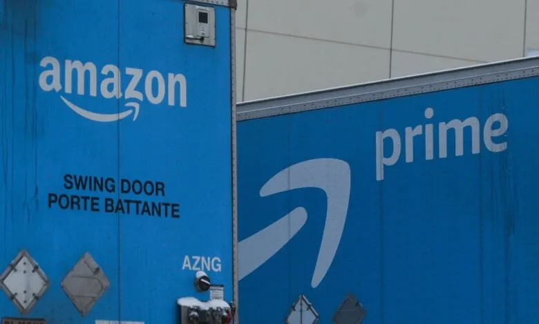 Two blue Amazon delivery trucks with the Amazon and Prime logos.