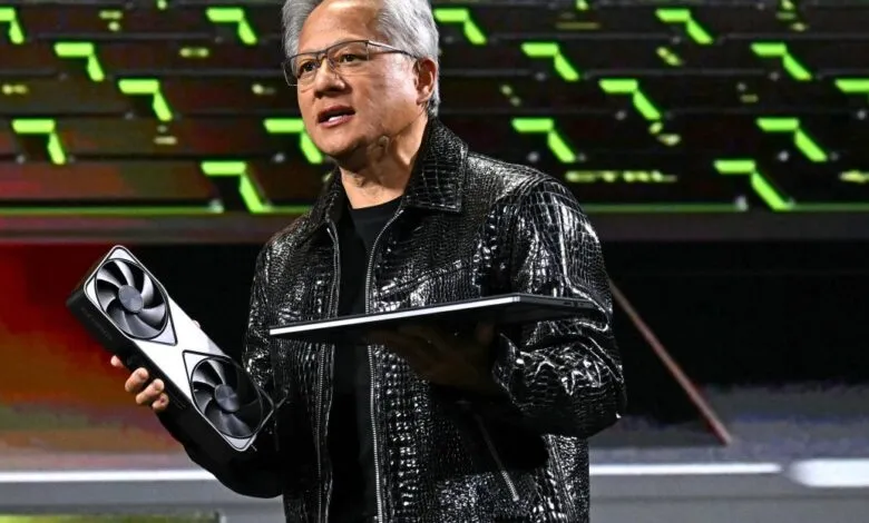 Jensen Huang presents NVIDIA GPU and laptop on stage.