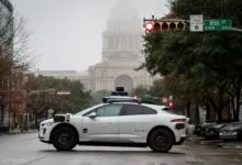 Waymo self-driving car at a red light with the Texas Capitol in the background.