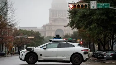 Waymo self-driving car at a red light with the Texas Capitol in the background.